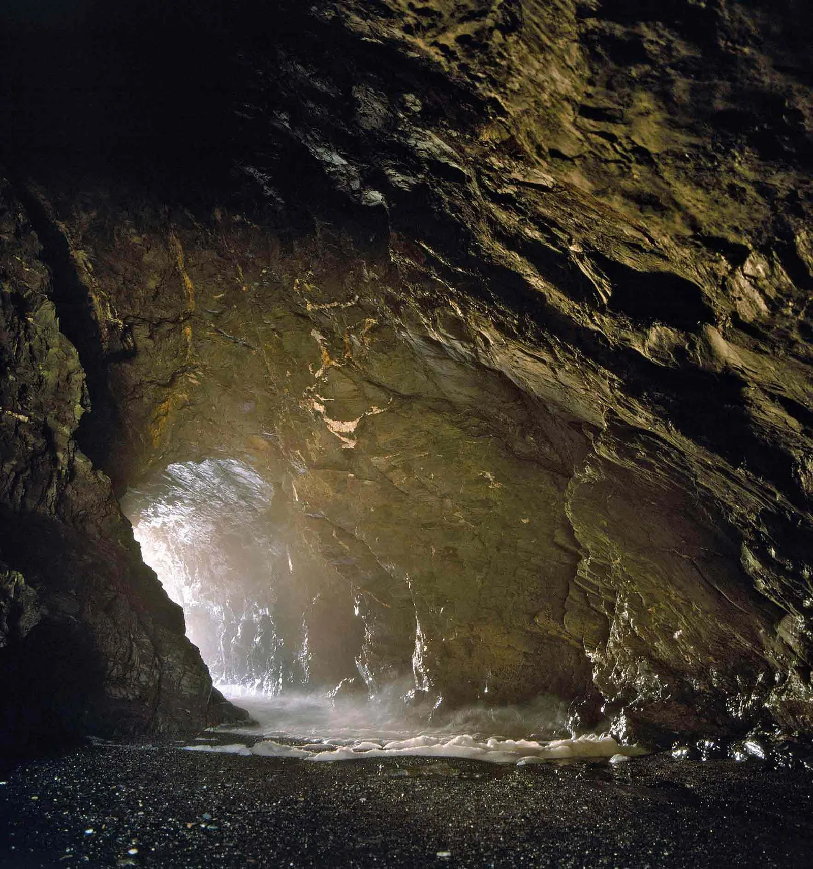 Inside Merlin's Cave, with sea spray at the far entrance