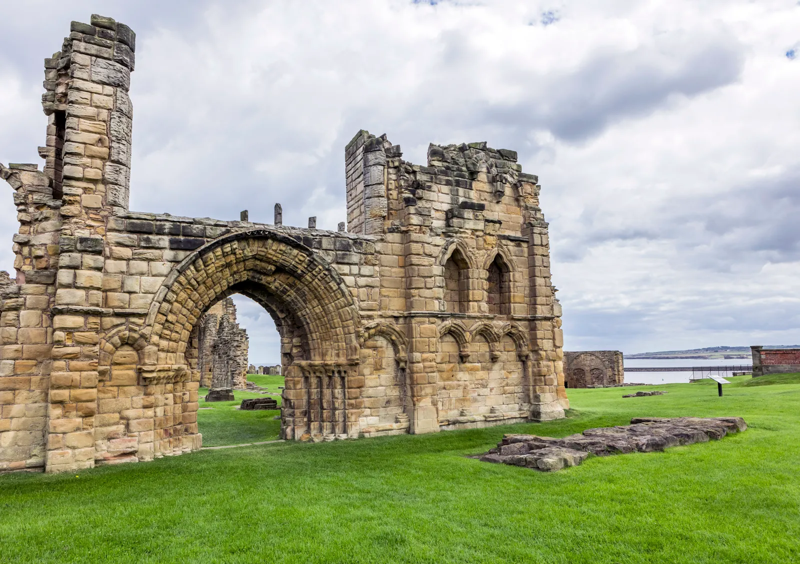 The priory's great Norman arch framing the ruined nave, with the sea beyond the headland