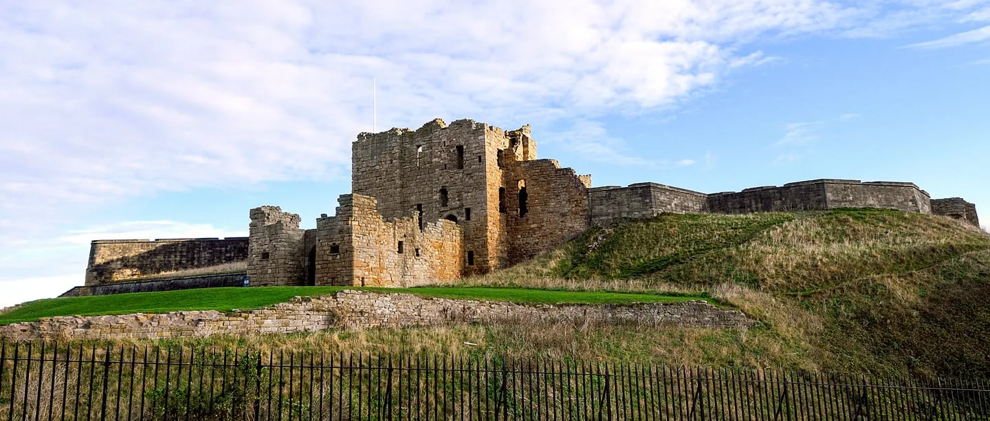 The gatehouse and later gun battery walls on the headland above an iron railing