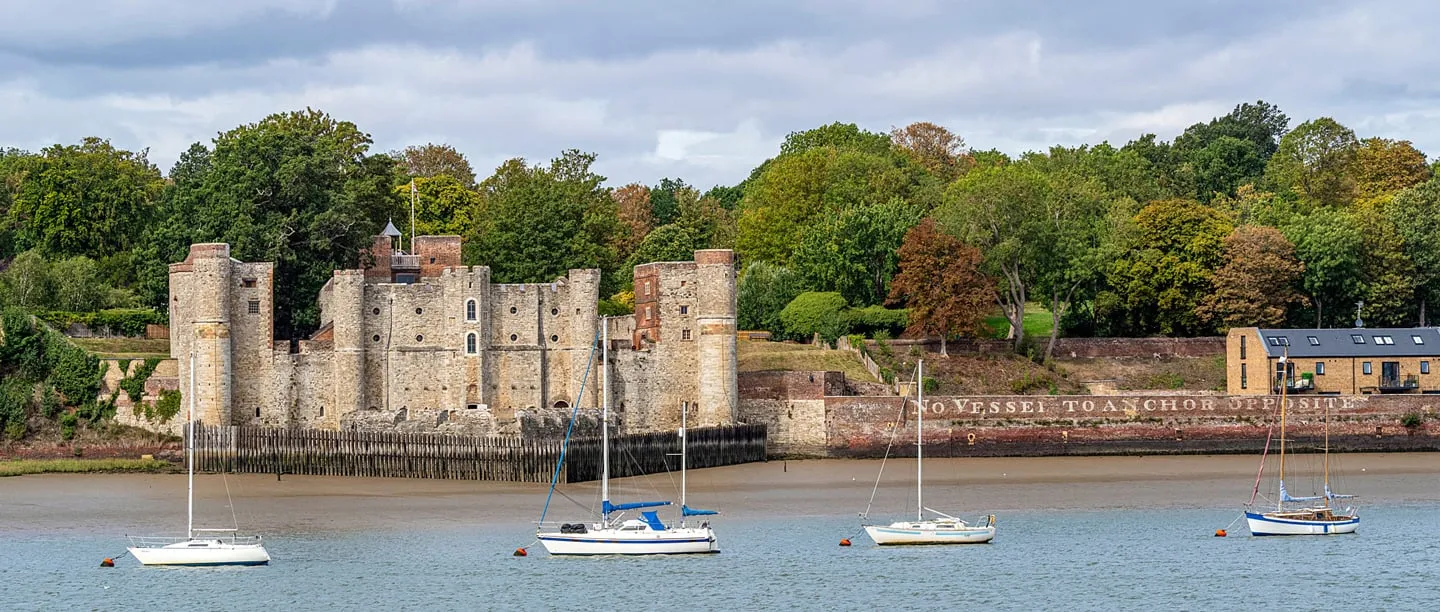 Upnor Castle's towers and timber palisade on the Medway at low tide, with yachts moored in front