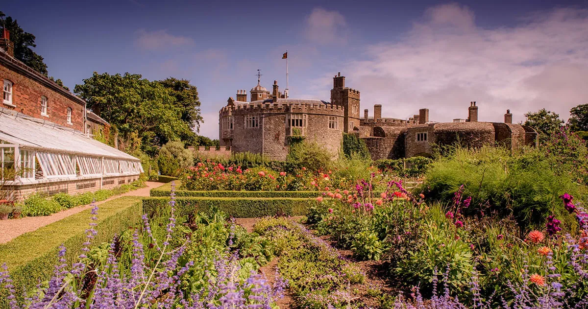 The castle above summer flower borders and the long glasshouse in the walled garden