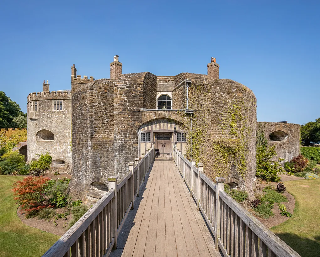 The wooden bridge across the dry moat to the castle gate under a clear blue sky