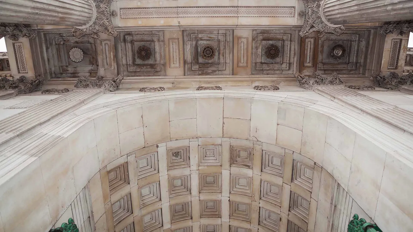 Looking up into the coffered vault of the arch past Corinthian capitals