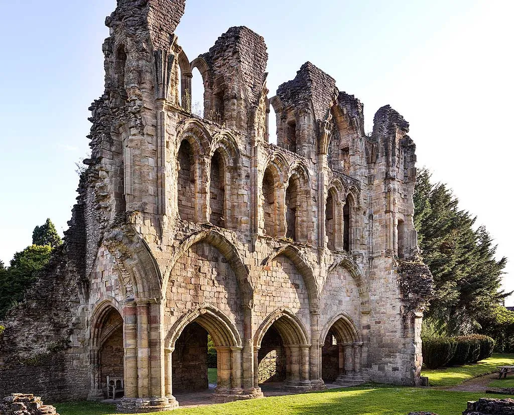 Tall ruined arcades of the south aisle of Wenlock Priory church in evening light