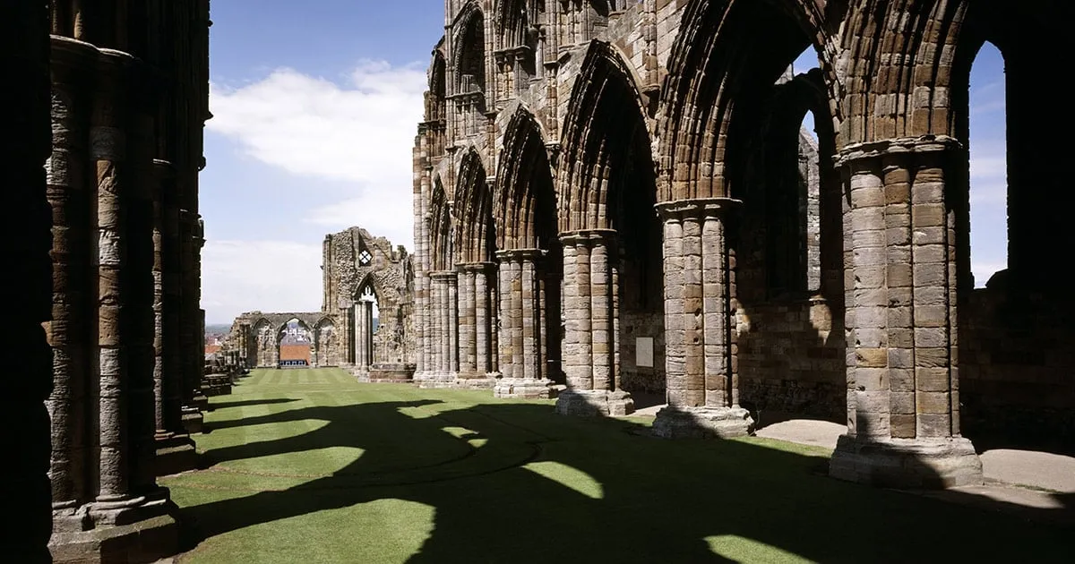 Looking down the nave between the columns, with long shadows on the grass