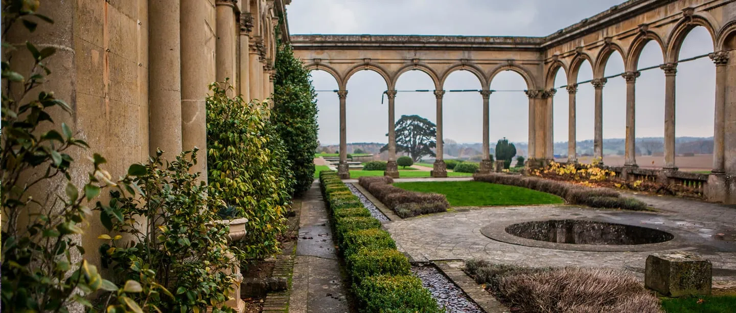 A colonnade of stone columns and camellias leading to the conservatory arches