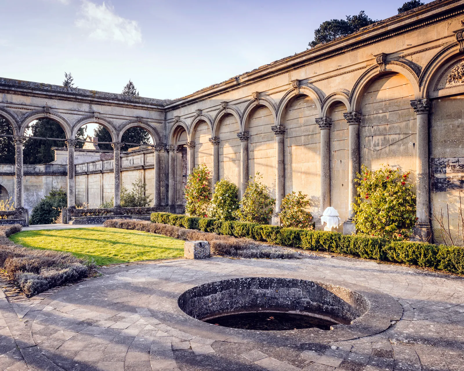 Inside the roofless conservatory: arcades, camellias and a sunken pool in evening light