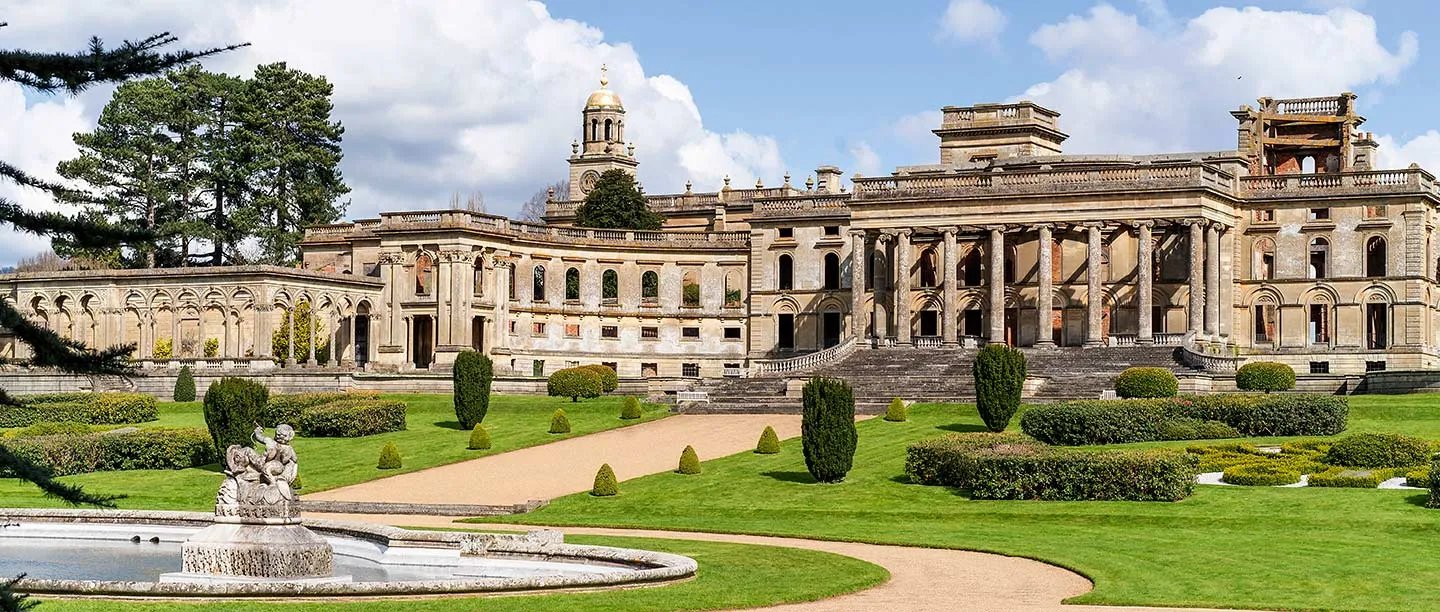 The conservatory and clock tower beyond a cherub fountain and sweeping lawns