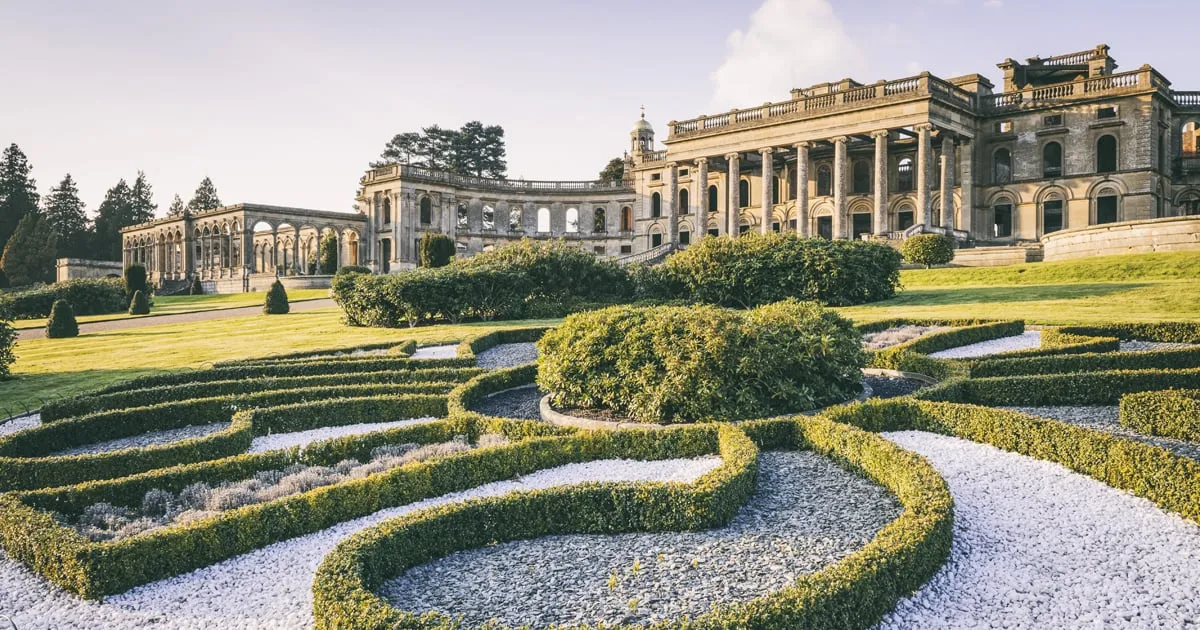 Curving box parterres with white gravel in front of the conservatory and the ruined house