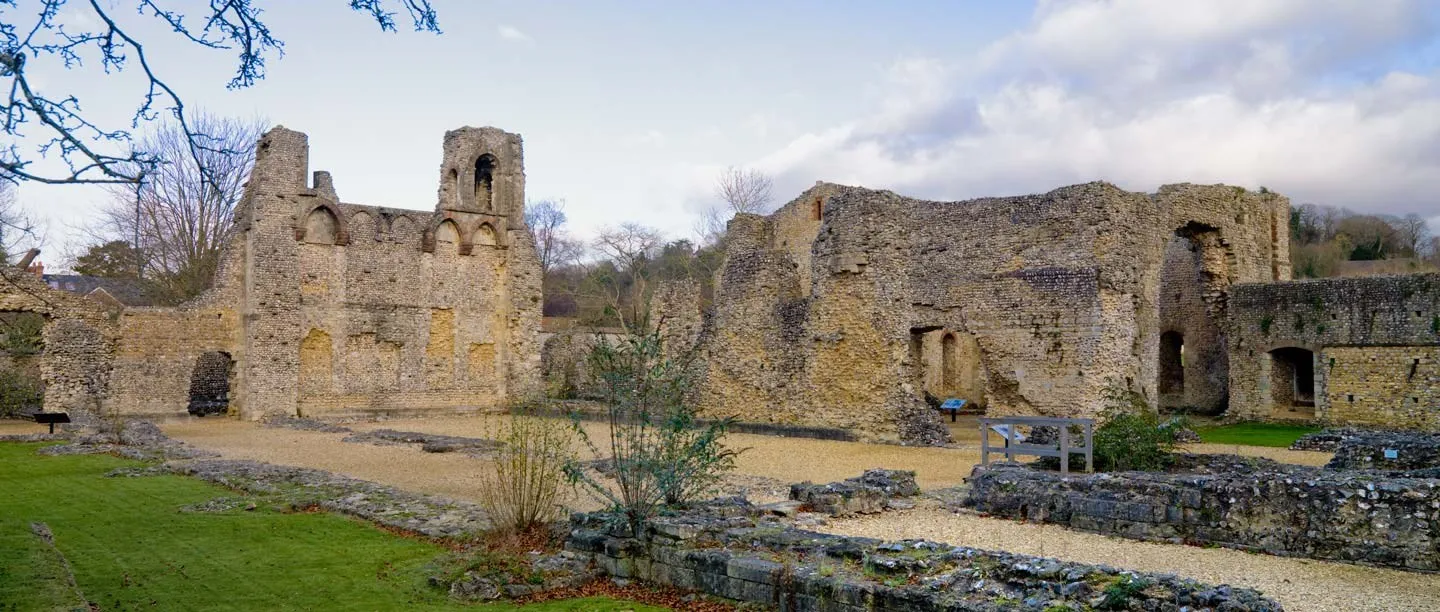 The flint walls, arches and window openings of Wolvesey's ruined bishop's palace under a cloudy winter sky