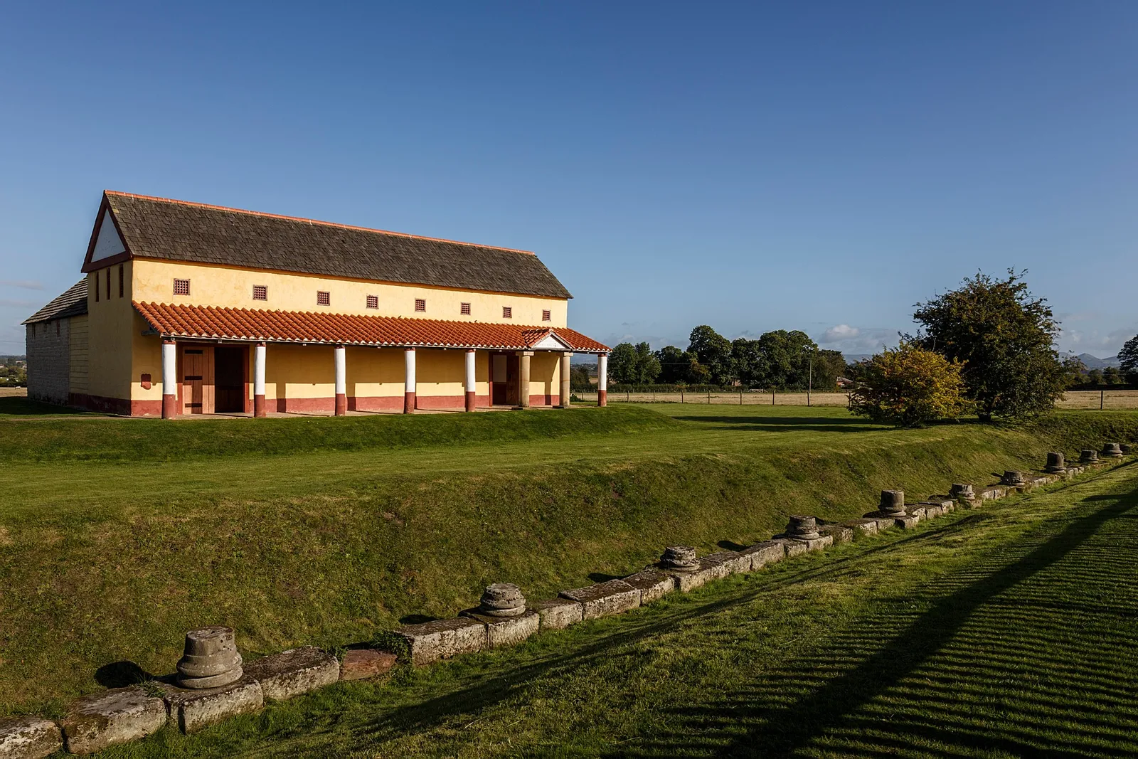 The reconstructed Roman town house with its colonnade and tiled roof beside a row of column bases
