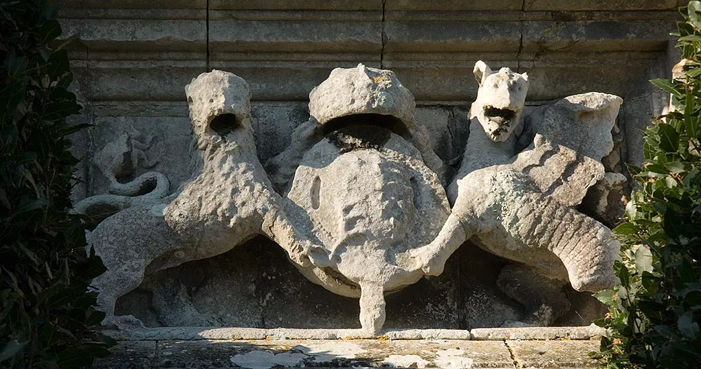 The weathered stone royal arms of Henry VIII carved above the entrance to Yarmouth Castle, a shield held by a lion and a dragon